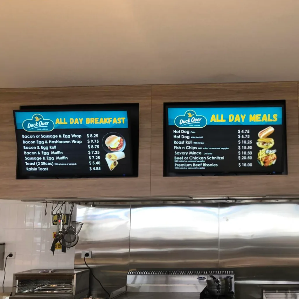 Digital menu board displays showing breakfast and meal options at a convenience store